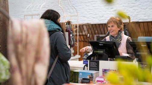 A volunteer serves a customer in the Tyntesfield Shop